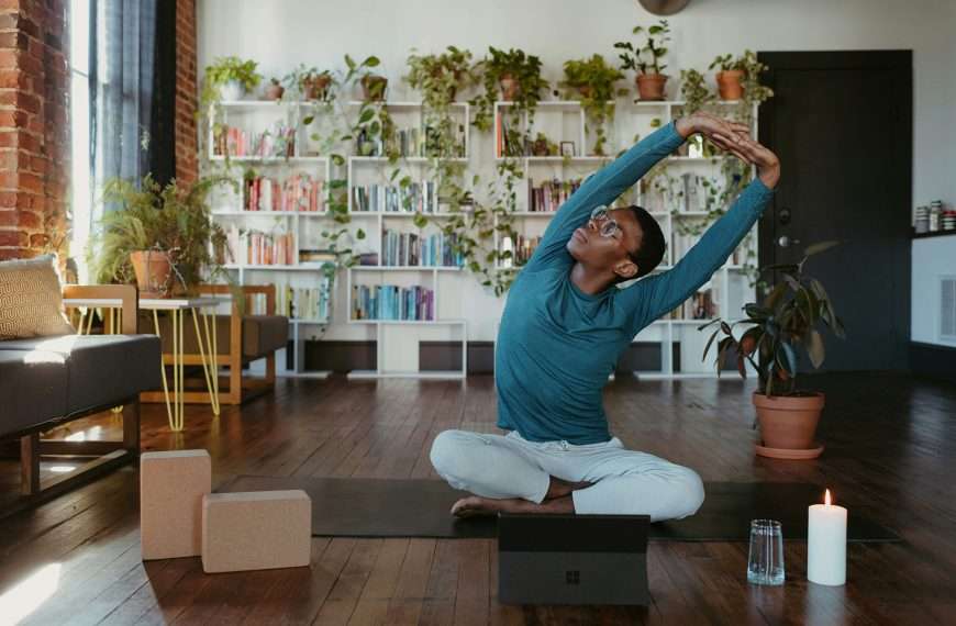 Man practicing consistency with movement by doing a seated side bend stretch at home
