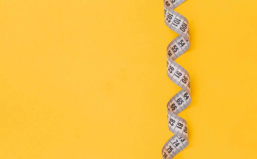 Yellow background with tape measure for body-neutral fitness goals without weight