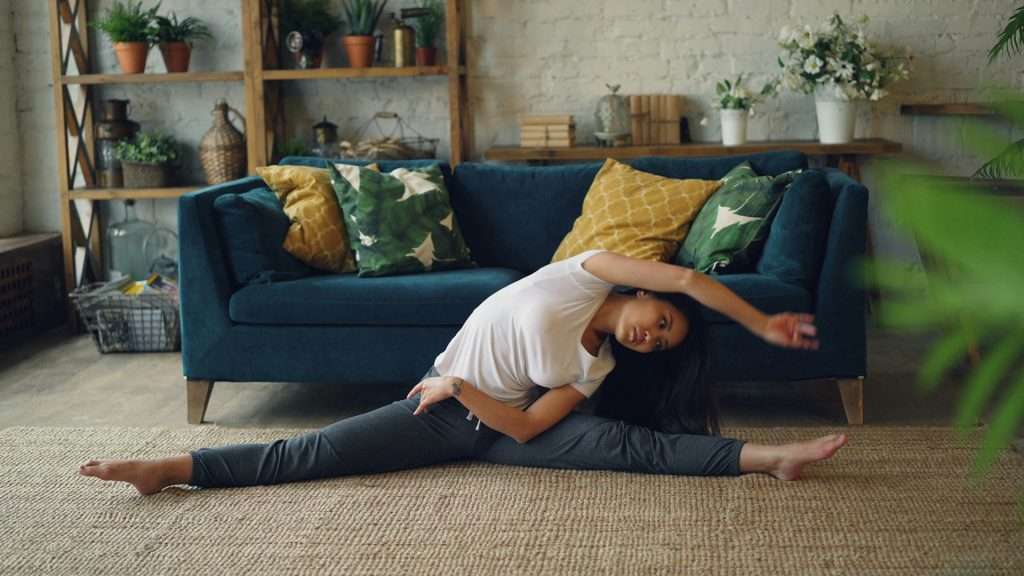 A person practicing a simple hip opener on their living room floor as part of their daily micro goals for flexibility routine.